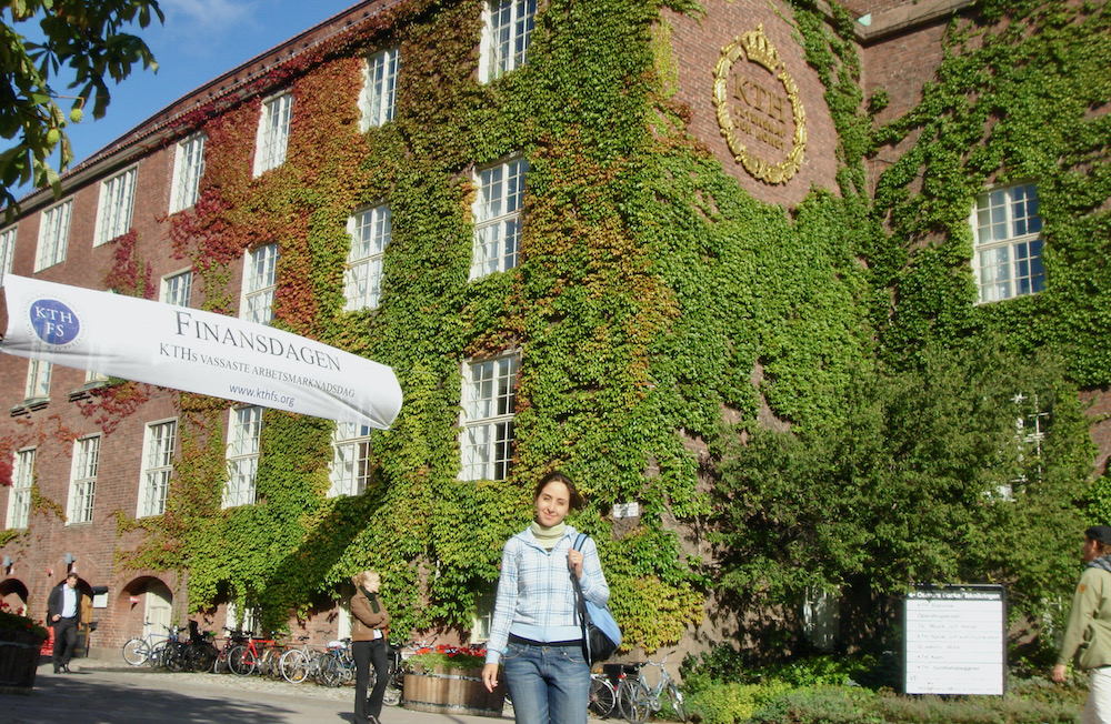 Oldouz is holding a backpack and standing in front of an ivy-covered red brick building.